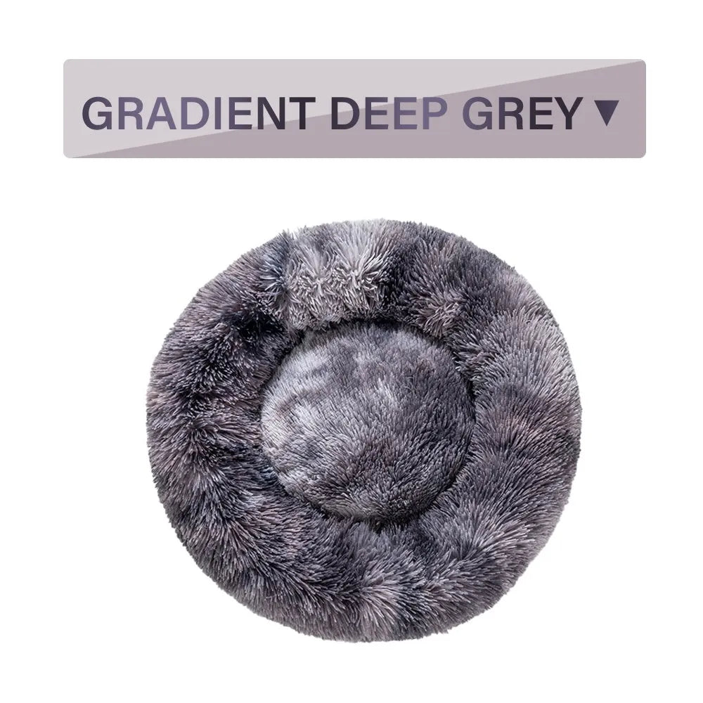 Fluffy donut-shaped dog bed in long plush fabric, shown in a light grey colour with a raised edge.