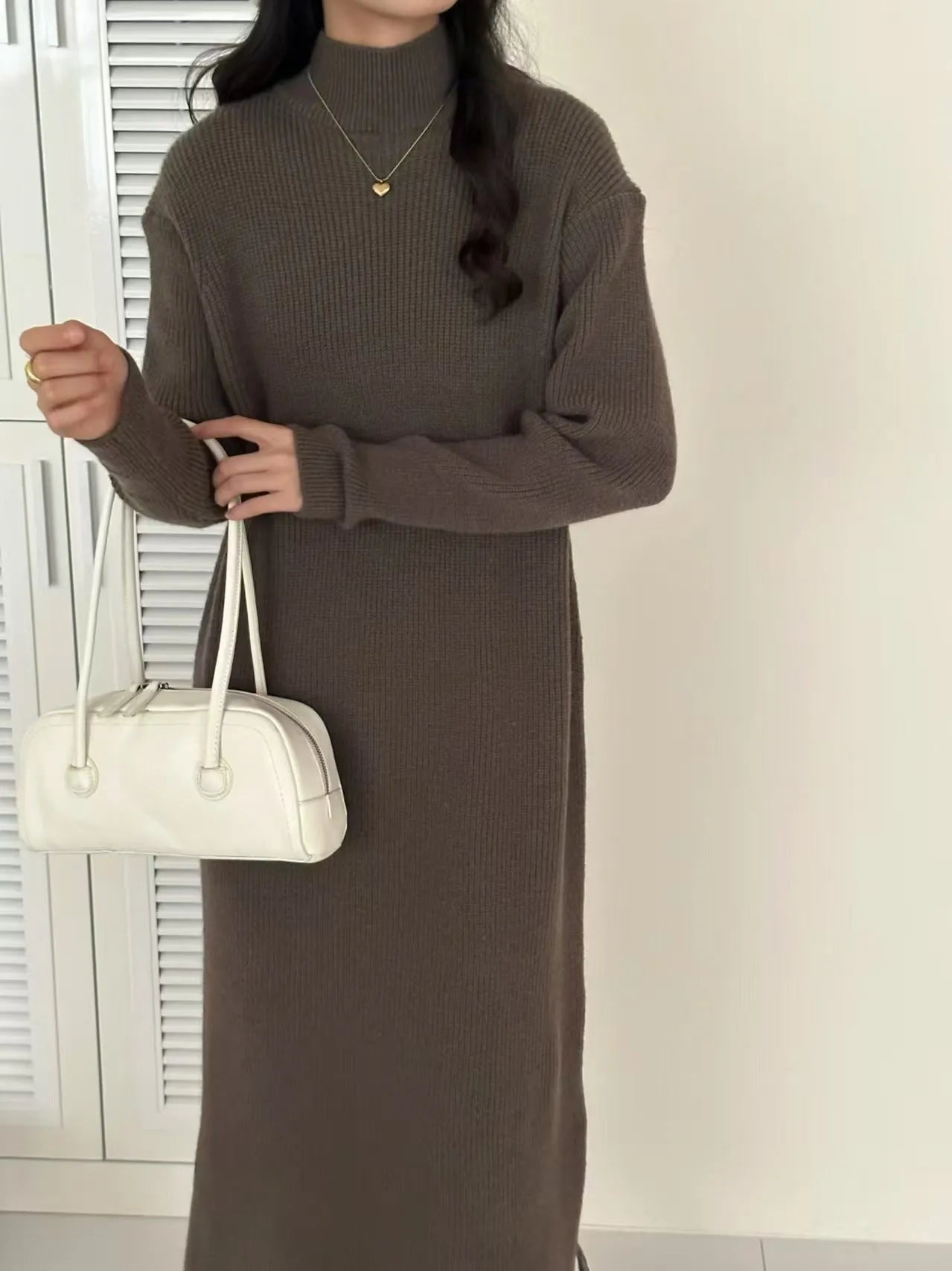Woman wearing a beige half-turtleneck, high-waisted, knee-length acrylic knit dress.