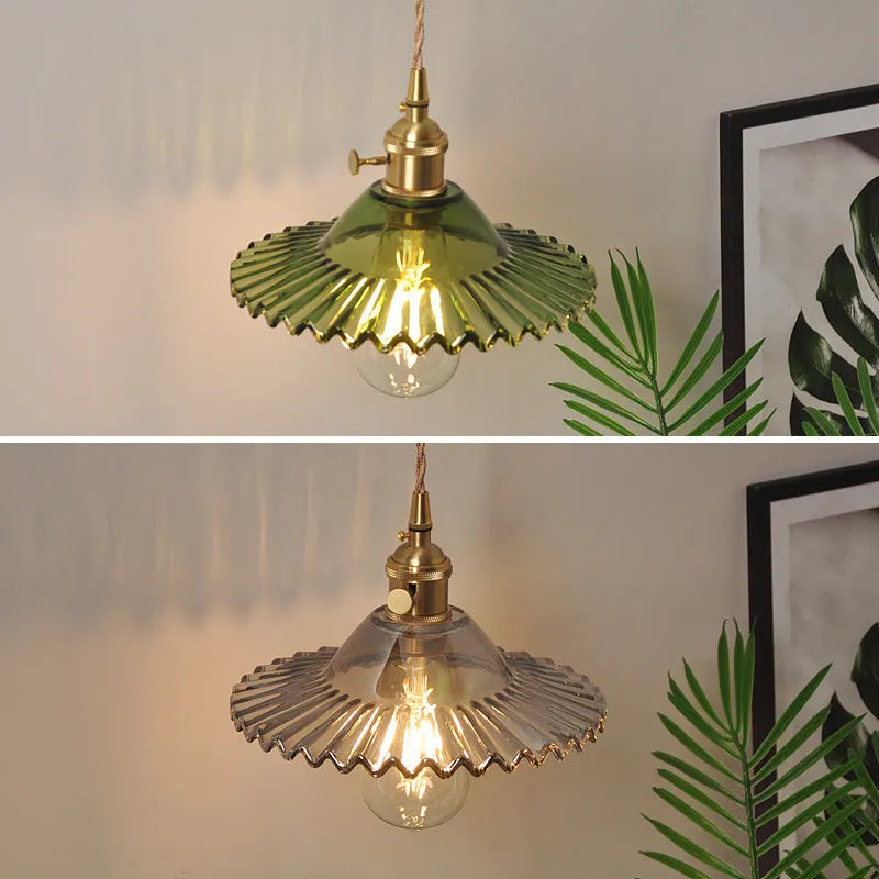 Brass lotus-shaped wall lamp with glass shade in choice of six colours on a plain wall.