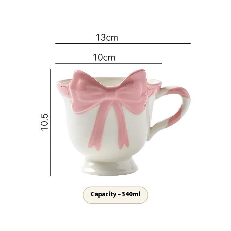Ceramic mug with a heart and bow design in black pink and white powder colour options.