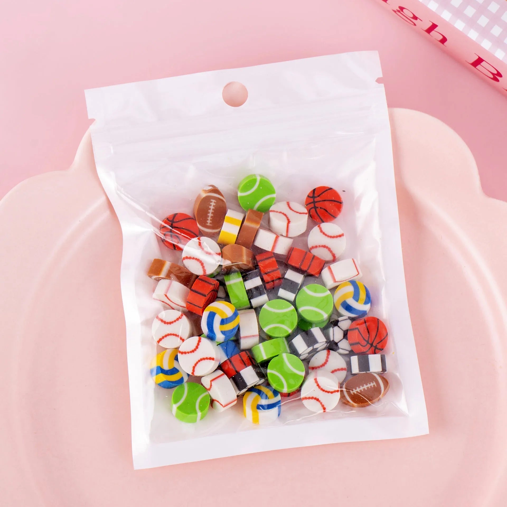 50 colourful cartoon mini erasers in shapes of fruits, animals, and cakes, displayed next to a pearlescent film bag.