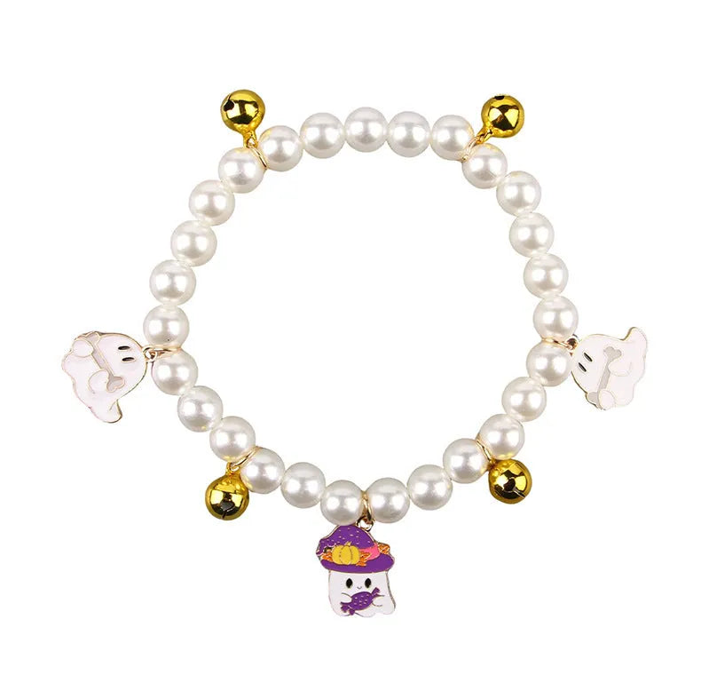 Close-up of a simulated pearl cat collar with a detailed Halloween pumpkin charm, showing the purple ghost design variant.
