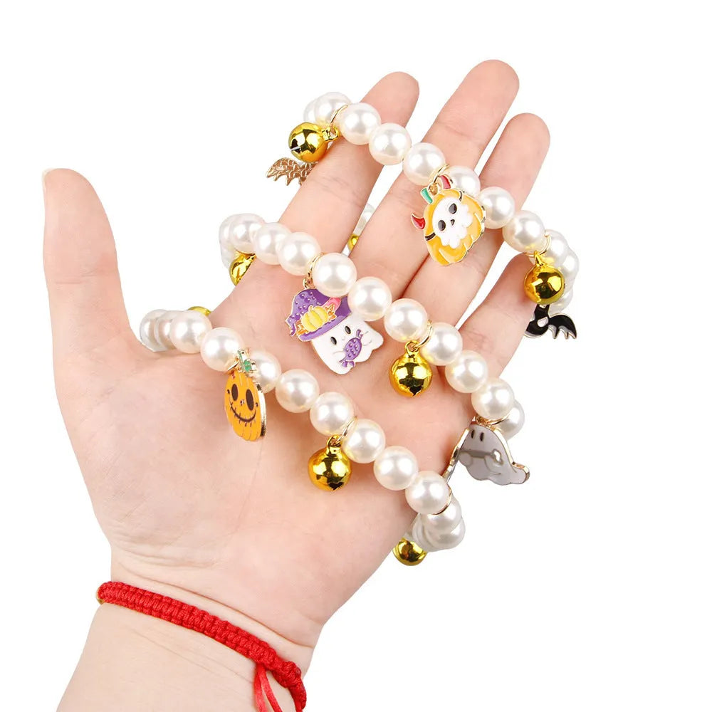 Close-up of a simulated pearl cat collar with a detailed Halloween pumpkin charm, showing the purple ghost design variant.