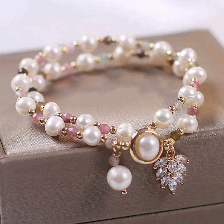 Women's double-layer strawberry quartz crystal bracelet with a red lucky cat charm on a white background.