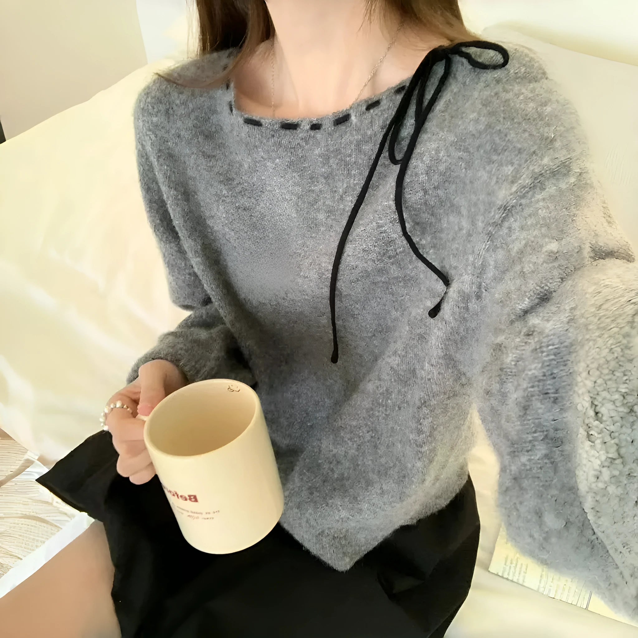 A grey women's loose-fitting long-sleeve knitwear pullover top on a hanger.