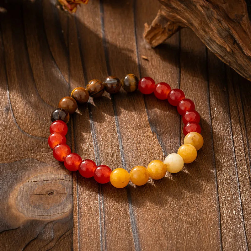 Long natural stone beaded sweater chain necklace and matching bracelet in bohemian style on a grey background.