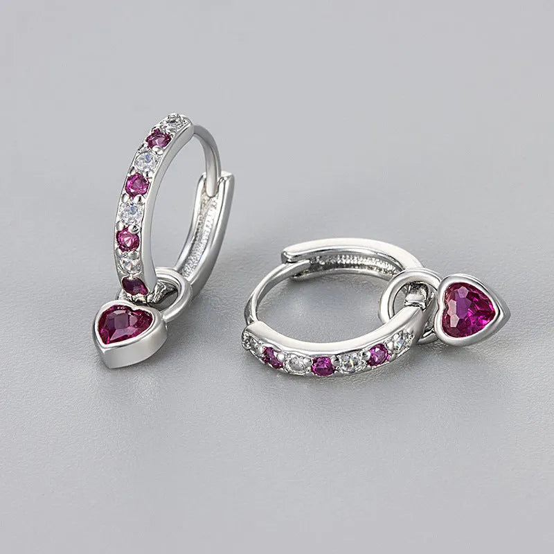 A pair of women's heart-shaped clip earrings with a coloured gemstone centre, available in gold or white gold colour metal.
