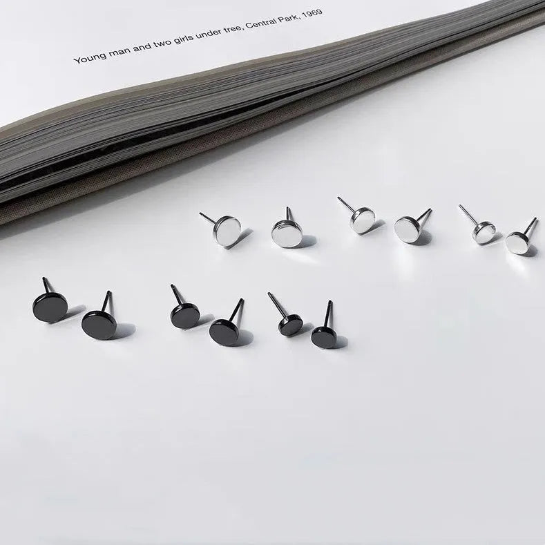 A pair of simple round S999 sterling silver flat ear bone studs on a plain background.