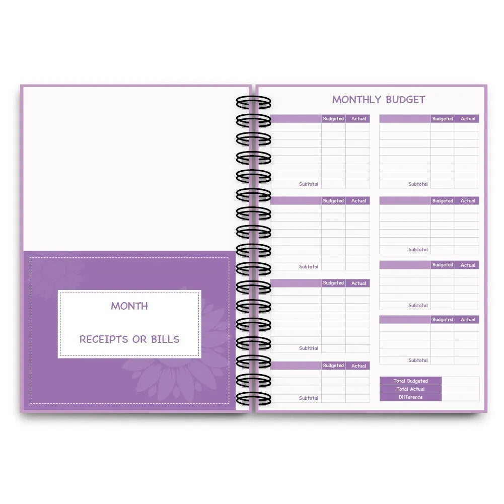 Purple coil-bound budget book open showing monthly financial planning layout with stickers and paper clips