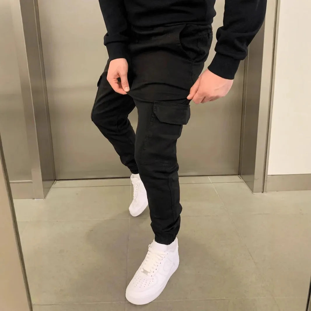 Man wearing loose light blue casual trousers with patch pockets and an elasticated waist.