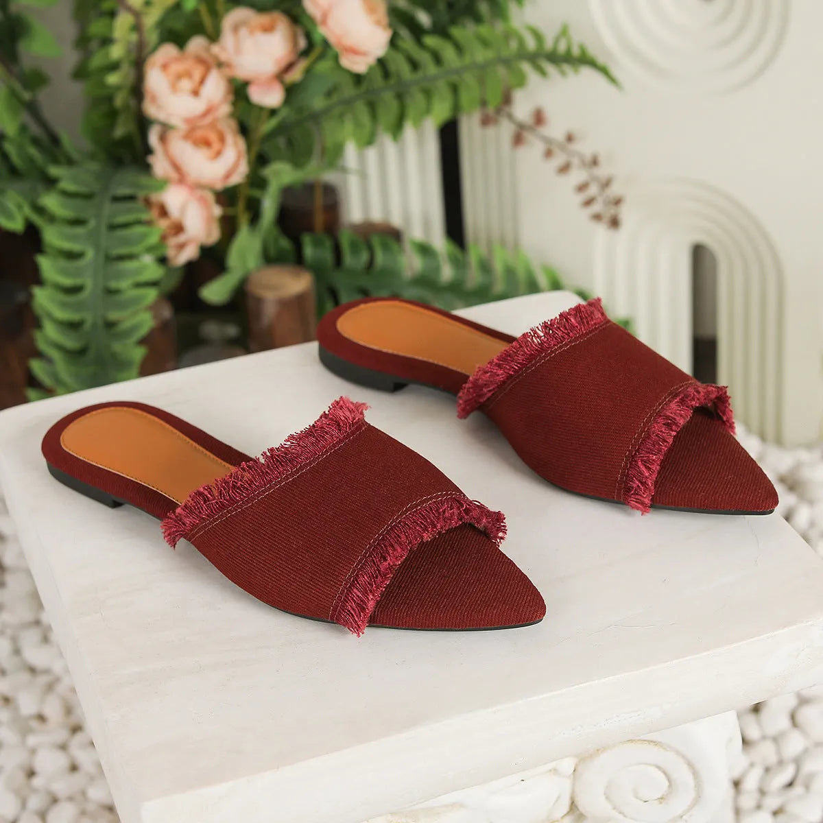 Women's denim flat slippers with leather lining and a tassel detail in various solid colours.
