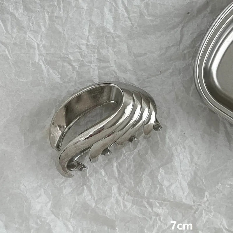 Assortment of silver metal hair claw barrettes with various designs including bows, pearls, and geometric shapes.